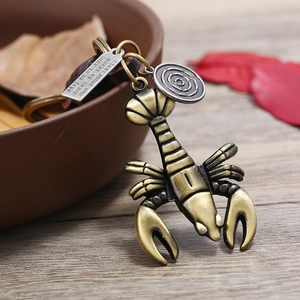 Vintage bronze alloy lobster keychain with engraved tag on a rustic wooden desk