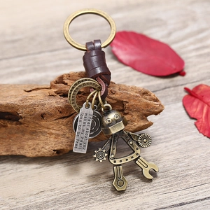 Retro bronze robot keychain with brown braided leather strap on a rustic wood background