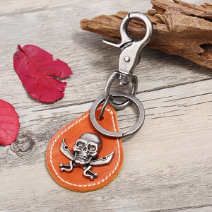 Vintage leather skull keychain with crossbones and pirate theme on wood background