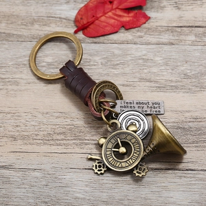 Vintage leather keychain with brass ring, trombone charm and engraved metal plate on wood
