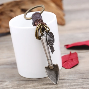 Retro handmade leather keychain with vintage metal shovel pendant on white ceramic cup