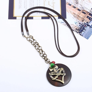 Retro long necklace with heart pendant on brown cord and wooden base over white surface