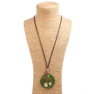 Long collier rétro en cordon ciré avec pendentif vert et breloque cerise sur présentoir