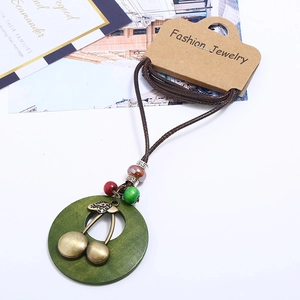 Sautoir rétro punk avec disque en bois vert, cerise en bronze et cordon de cire