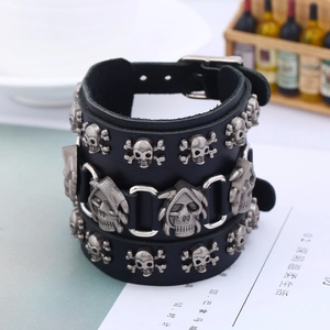 Punk style wide black leather bracelet featuring skull studs and adjustable buckle