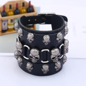 Wide black punk leather bracelet for men featuring multiple rows of metallic skull charms