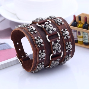 Close-up of wide punk leather bracelet featuring silver skull and crossbones studs