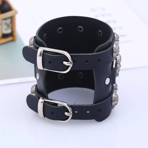 Macro detail of black leather punk wristband featuring silver skull studs and dual buckles