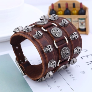 Macro detail of brown leather punk bracelet featuring silver skull studs and metal buckles