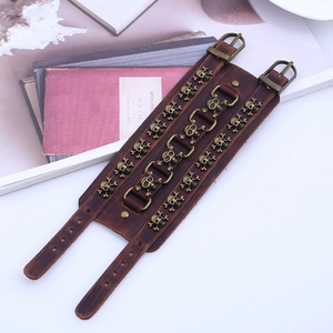 Detail of wide punk leather bracelet featuring three rows of bronze skull rivets and dual buckles