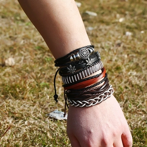 Retro multi-layer woven leather bracelet set featuring vintage leaf charms on grass