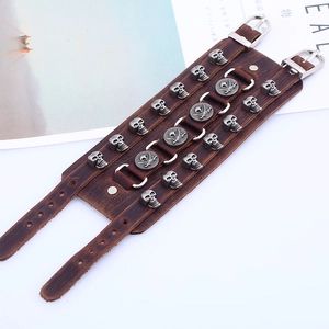 Detail of wide brown leather punk bracelet with silver skull studs and pirate emblems
