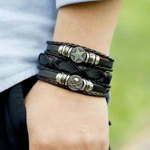 Close-up of men's layered leather bracelet featuring a skull charm and metal star icon