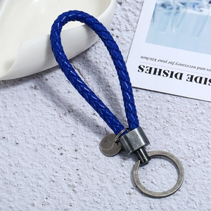 Detail of deep blue braided PU leather keychain with antique silver metal ring and circular tag