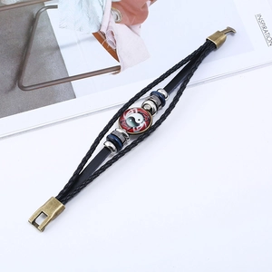 Close-up of woven leather bracelet featuring a red Yin Yang glass dome and bronze clasp
