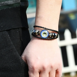 Braided leather bracelet with Yin Yang sun pendant on a wrist in natural light