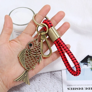 Detailed view of hollow fish pendant with bronze finish and red-black braided cord handle