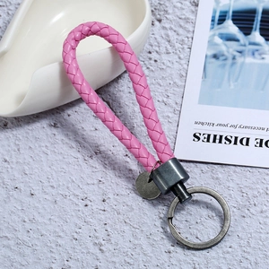Detail of pink woven PU leather keychain with antique silver metal ring and circular tag