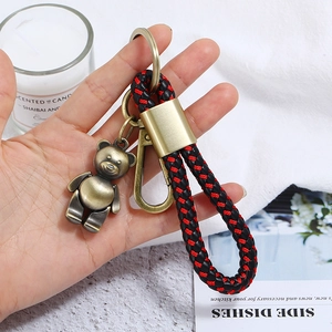 Detail of vintage bronze bear charm with red and black braided leather keychain cord