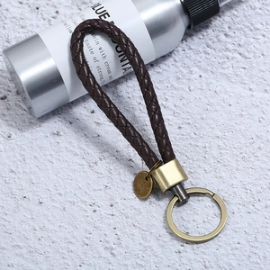 Detail of hand-woven dark brown leather keychain with vintage bronze metal ring on stone