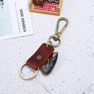 Retro genuine leather keychain with bronze cross shield pendant on white stone background