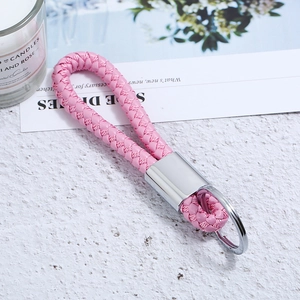 Close-up of pink woven leather keychain with polished silver metal ring on marble surface
