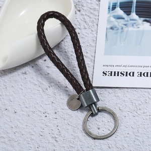 Detail of dark brown braided PU leather keychain with antique silver metal ring and tag