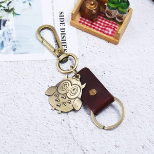 Vintage bronze owl leather keychain with large carabiner on white textured surface
