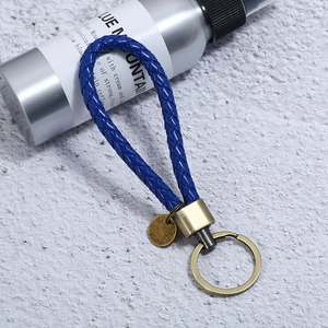 Close-up of blue braided leather keychain with antique bronze metal ring and blank tag