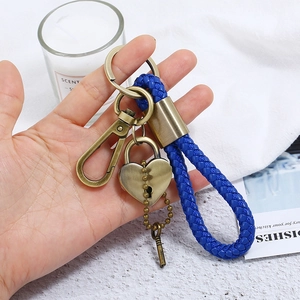 Blue braided leather keychain with vintage bronze heart lock and key charms in hand