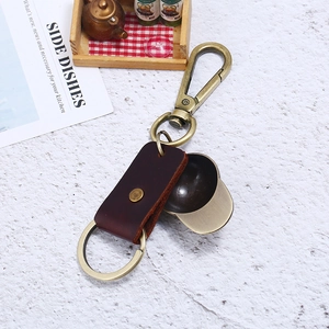 Vintage bronze hat pendant keychain with dark brown leather details on white background