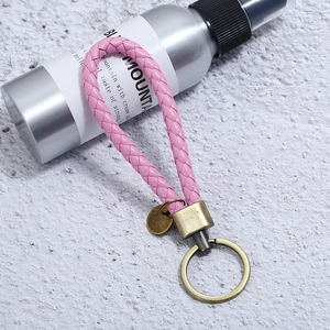Detailed close-up of a pink braided leather keychain with vintage bronze metal ring