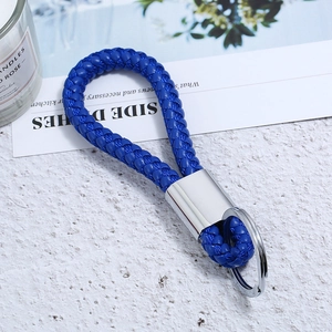 Royal blue braided leather keychain with silver metal ring on a minimalist desk background