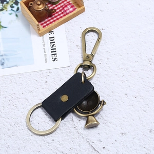 Retro leather keychain with brass carabiner and miniature globe charm on stone background