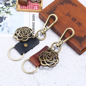 Vintage bronze flower leather keychains in black and brown styles on wooden background