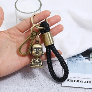 Detail of vintage bronze Buddha charm on black braided leather keychain with lobster clasp