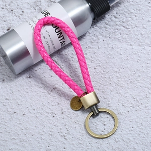 Detail of pink braided leather keychain with antique bronze ring on a stone surface