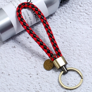 Detail of red and black braided leather keychain with vintage bronze metal ring and tag