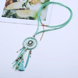 Close-up of bohemian mint green dreamcatcher necklace with gemstone and tassels