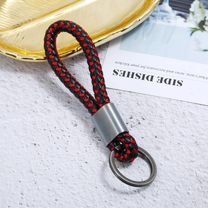 Detail of red and black woven leather keychain with metallic ring on a gold leaf tray