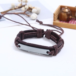 Détail d'un bracelet en cuir tressé vintage avec cordons réglables et plaque en métal à graver
