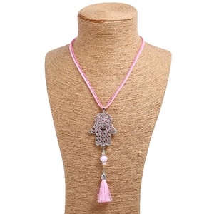 Pink Hamsa hand necklace with sparkling rhinestones and a long tassel on a white background