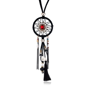Detail of dreamcatcher pendant with red gemstone and black tassels on a long necklace