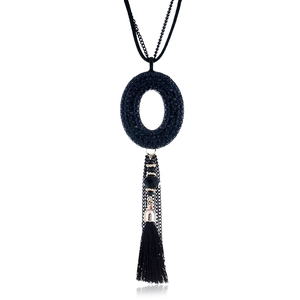 Dettaglio di una lunga collana bohémien con strass scuri e frange di seta nera