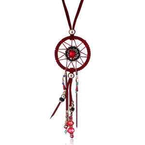 Detail of bohemian dreamcatcher necklace with burgundy suede cords and red gemstone charms
