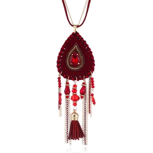 Dettaglio della collana boho con pendente a nappe rosse e accenti di perline dorate