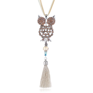 Dettaglio di una collana a gufo con strass color champagne e nappe in seta elegante