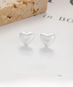 Macro shot of S925 sterling silver heart earrings with a brushed metal finish and texture