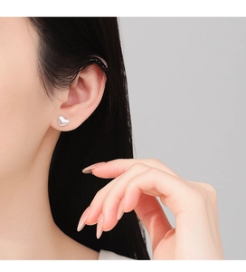 Close-up of minimalist brushed S925 sterling silver heart stud earring on model ear