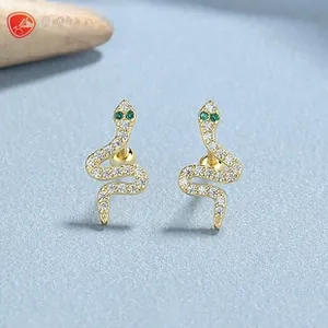 Detailed view of snake-shaped earrings in gold finish with sparkling white and green zircons